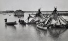 Two teepees are surrounded by water during Spring