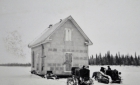 Tractors moving a house on skids during winter