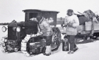 Men refuelling a tractor sled train on frozen land