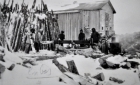 Men splitting logs for construction in winter